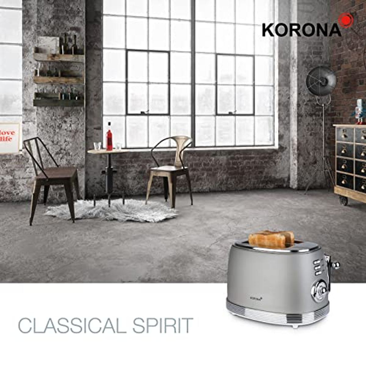 Ein Toaster im Retro-Stil auf einer Theke. Im Hintergrund sind ein Fenster, Stühle und ein Tisch zu sehen.