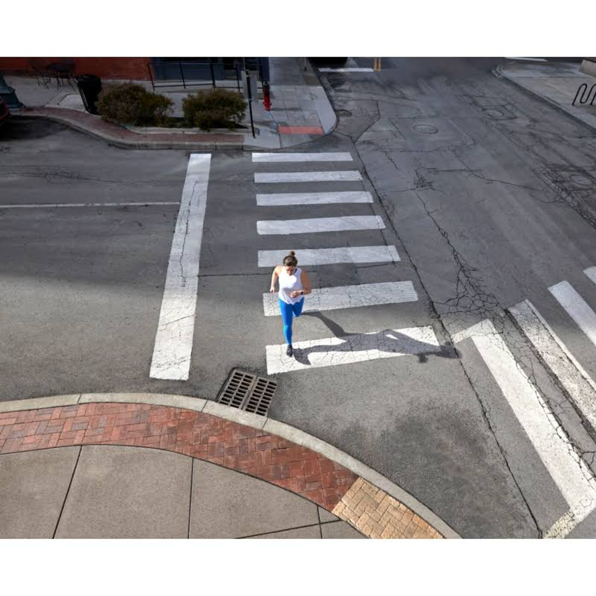 Kobieta biegnąca przez przejście dla pieszych. Widok z góry.