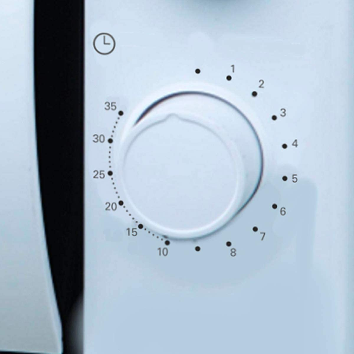 Biały panel sterowania kuchenki mikrofalowej. Okrągłe pokrętło z numerami i małym symbolem zegara.