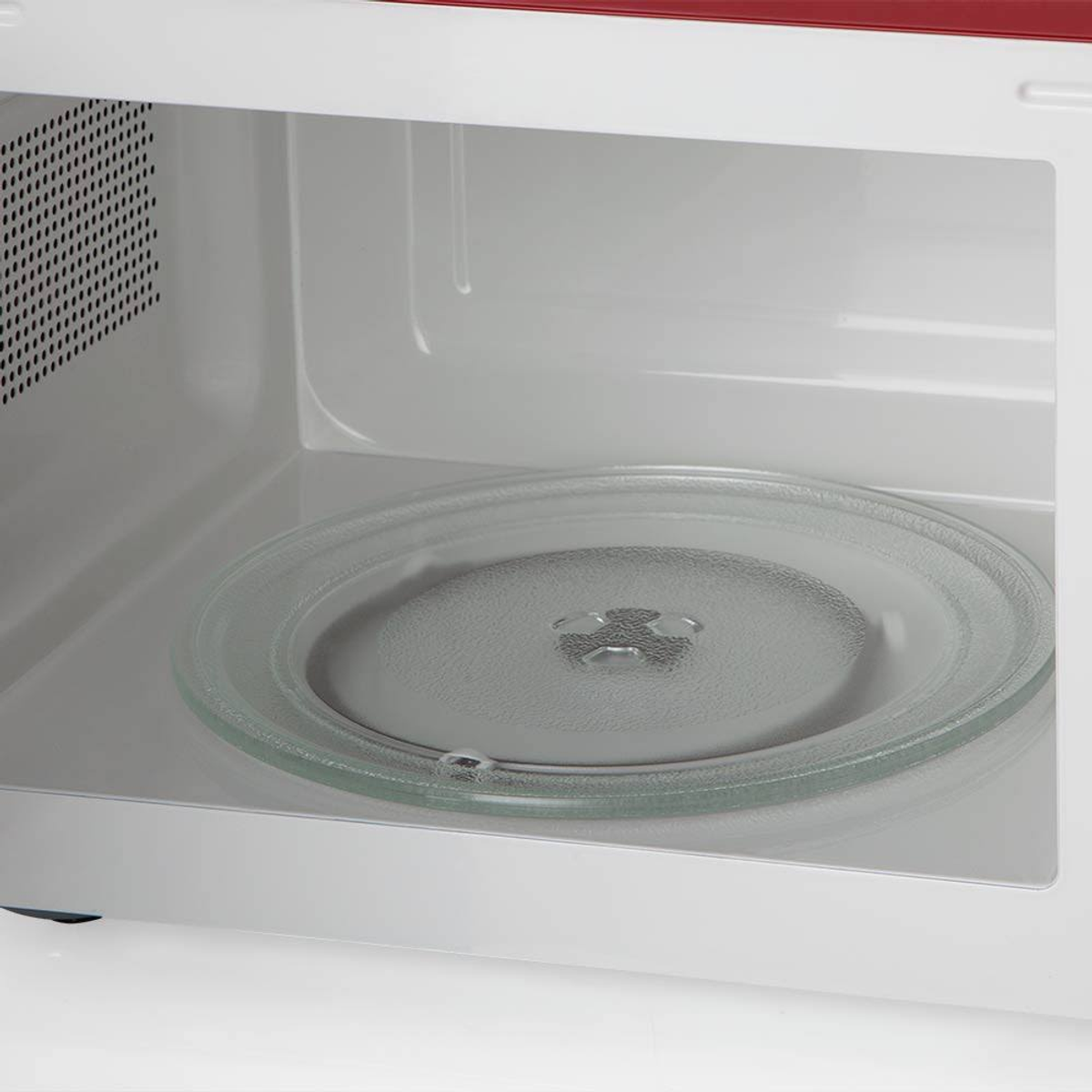 Wnętrze czerwonej kuchenki mikrofalowej ze szklanym talerzem.