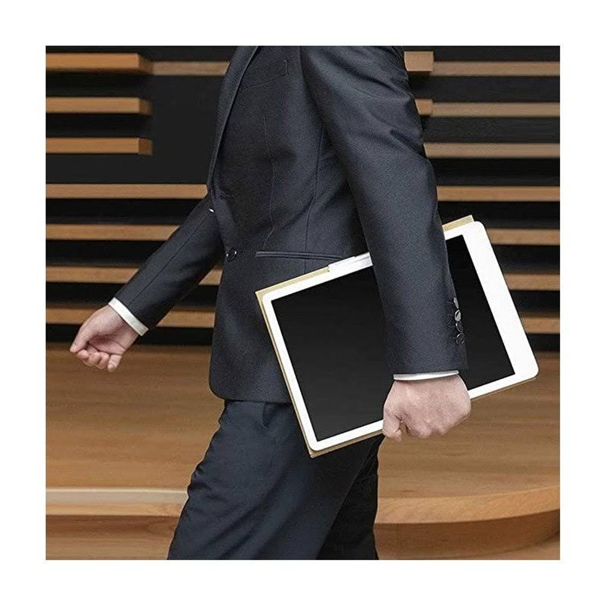 Una persona in giacca e cravatta tiene due tablet mentre cammina. Sfondo in legno.