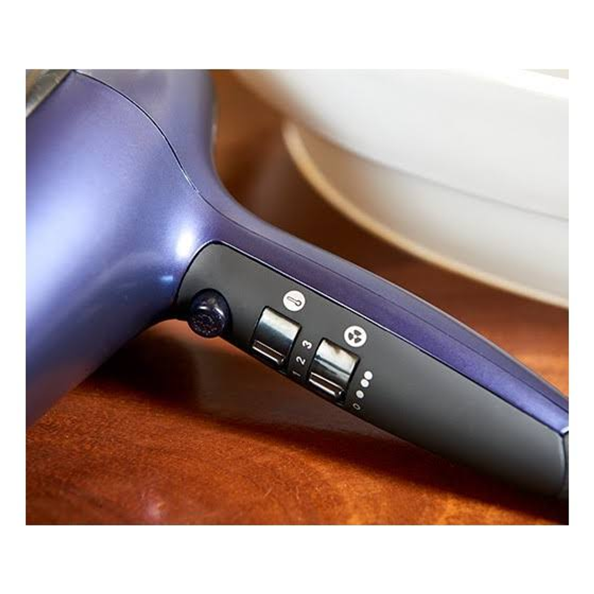 Zbliżenie fioletowej i czarnej suszarki do włosów z przyciskami ustawień.