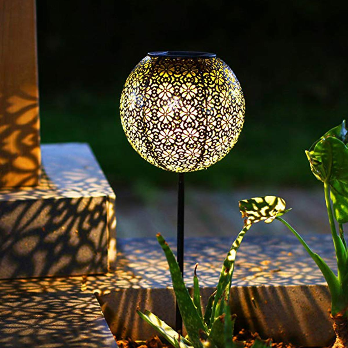 Eine dekorative, runde Solar-Außenlampe, die ein warmes Leuchten abgibt.