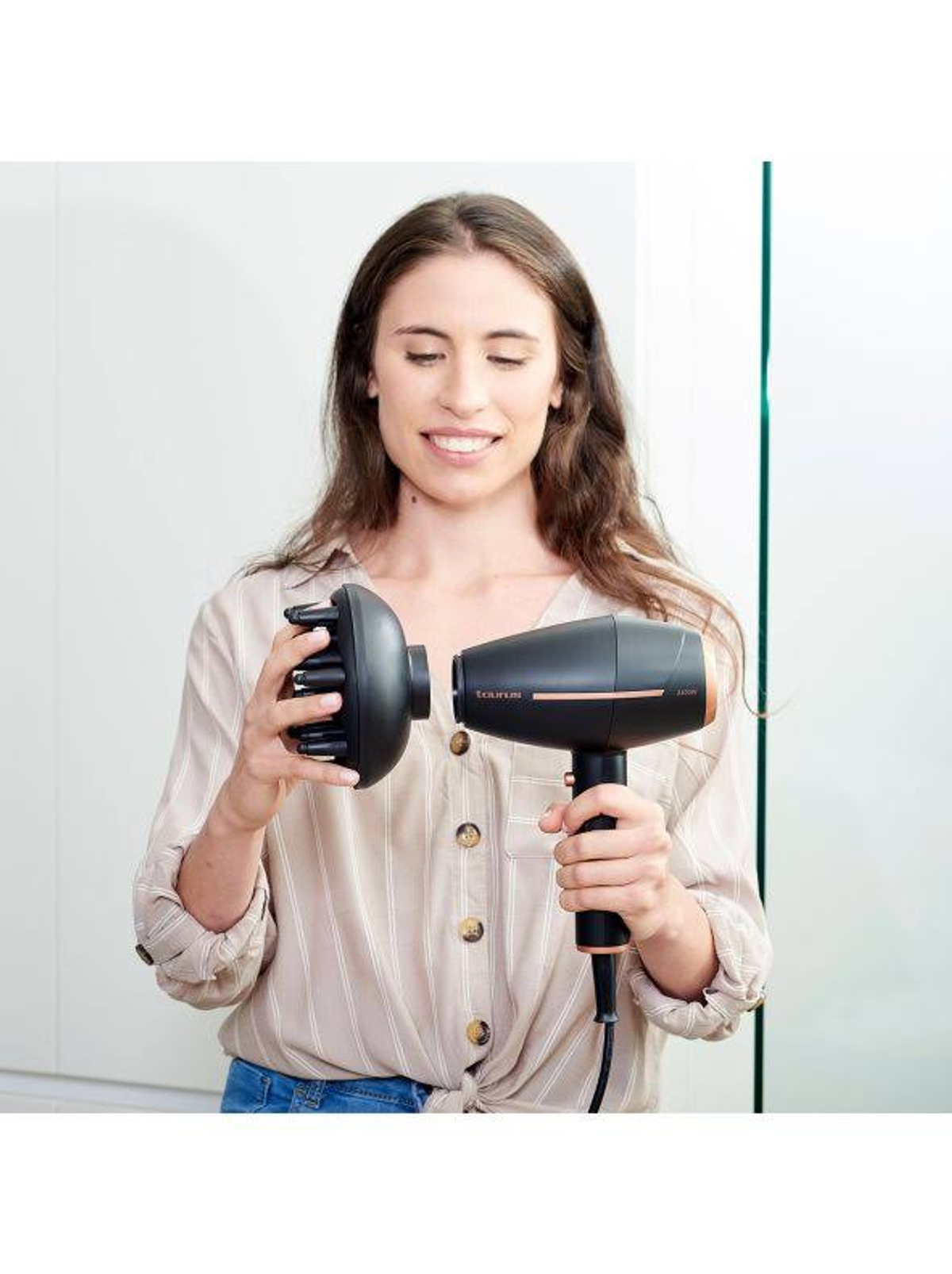 Kobieta trzyma suszarkę i dyfuzor, gotowa do połączenia. Tło: biała ściana i drzwi.