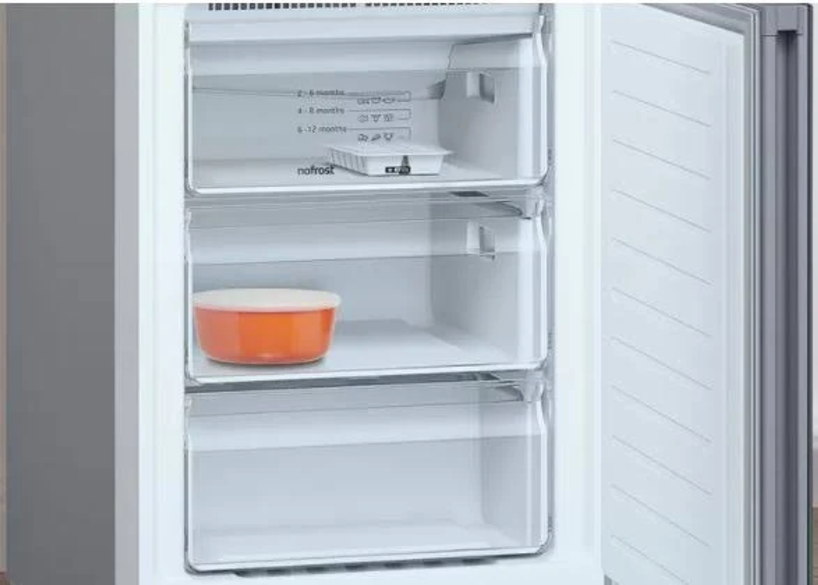 Interior de un frigorífico con cajones transparentes. Un cuenco naranja dentro.