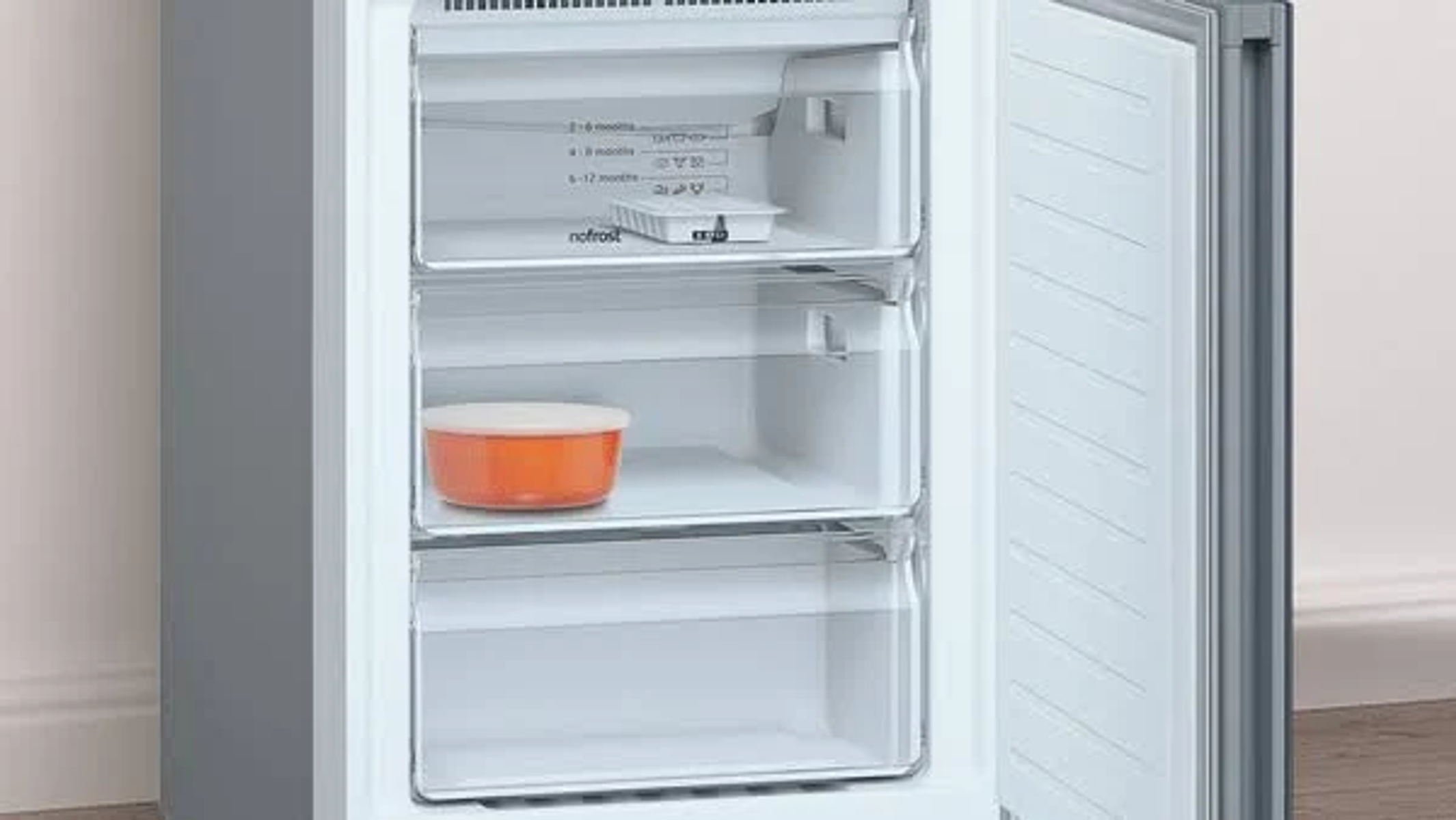 Congelador con puerta abierta. Tres cajones transparentes. Un cuenco naranja dentro.