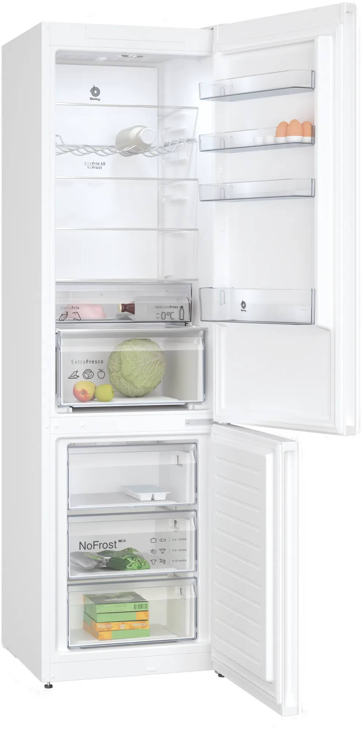 Refrigerador blanco abierto, muestra estantes con comida. La puerta está abierta. Se ven verduras y frutas.