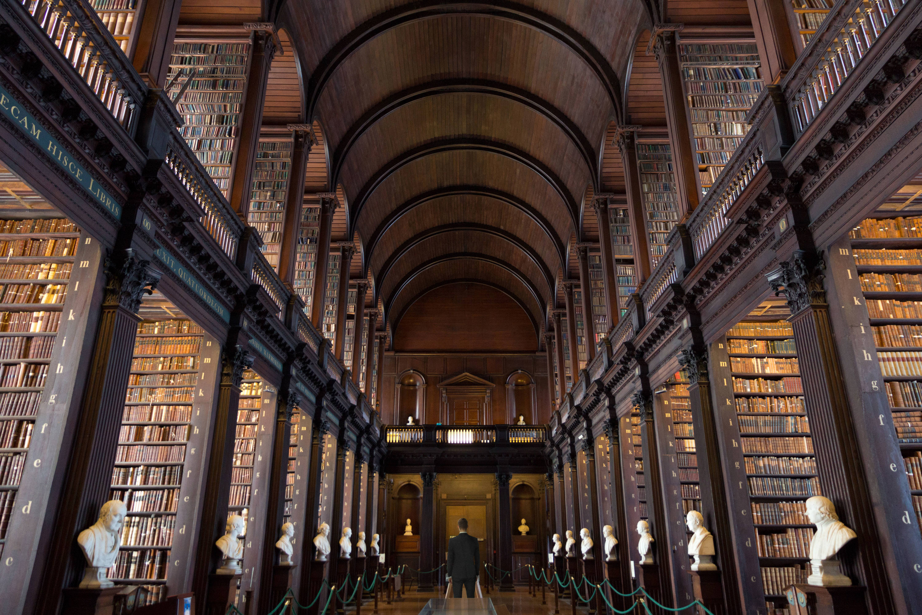 Innenraum einer Bibliothek mit Bücherregalen und einem Mann am Ende.