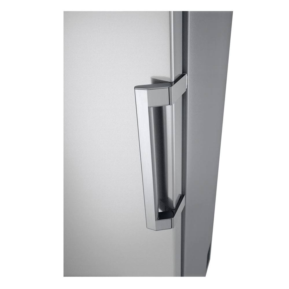 Primer plano del tirador de un frigorífico. Plateado y rectangular, sobre una puerta gris.