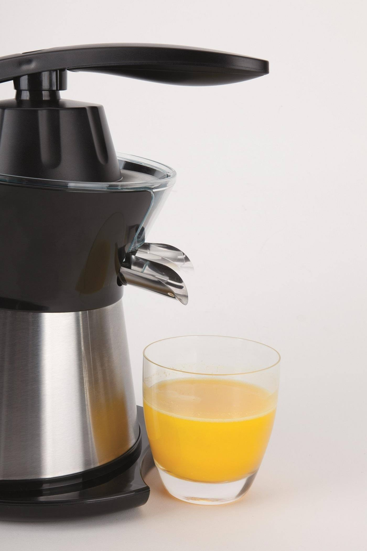 Exprimidor con vaso de jugo. Diseño negro y plateado. Un vaso transparente con jugo de naranja.