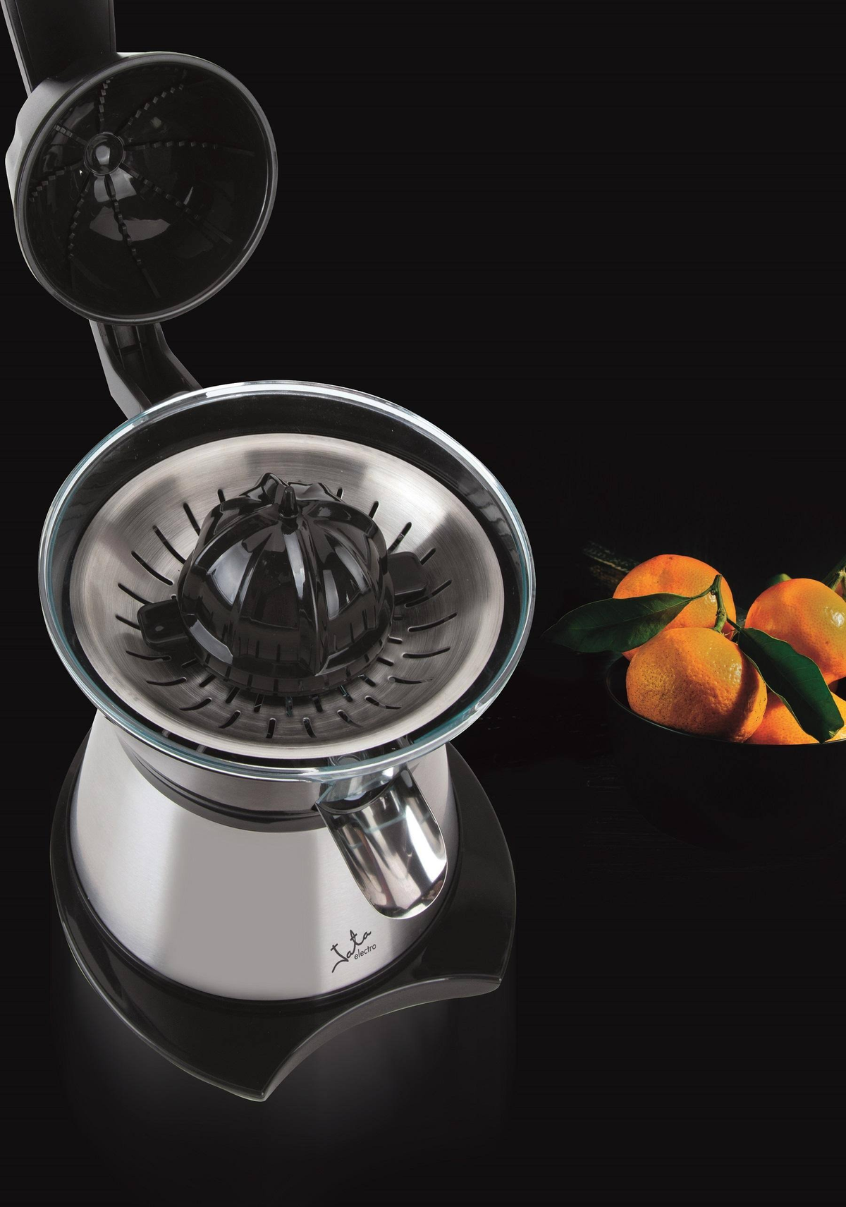 Exprimidor con naranjas y zumo. Cuenco de cristal y partes de acero inoxidable. Fondo oscuro.