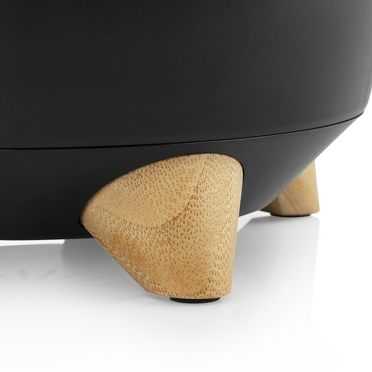 Czarny obiekt z drewnianymi nogami. Nogi są krótkie i skierowane na zewnątrz.