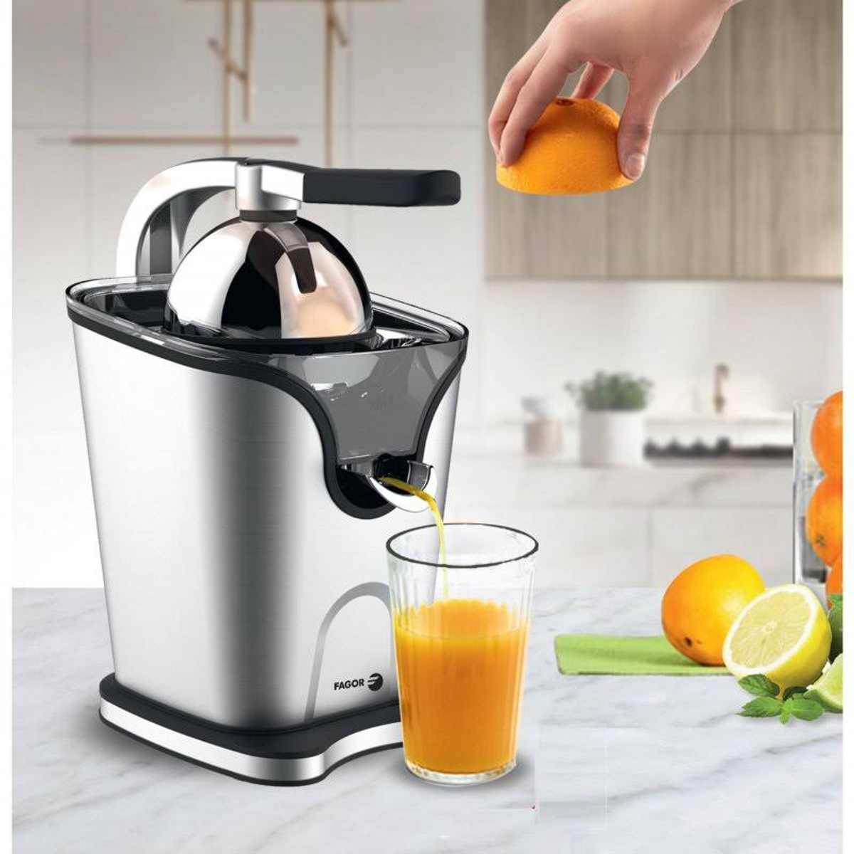 Exprimidora de cítricos con zumo en un vaso. Mano exprimiendo una naranja. Escena de cocina.