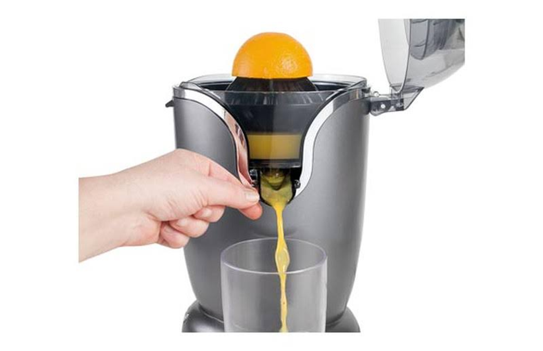 Mano che spremi un'arancia in un bicchiere usando uno spremiagrumi elettrico. Il succo scorre.