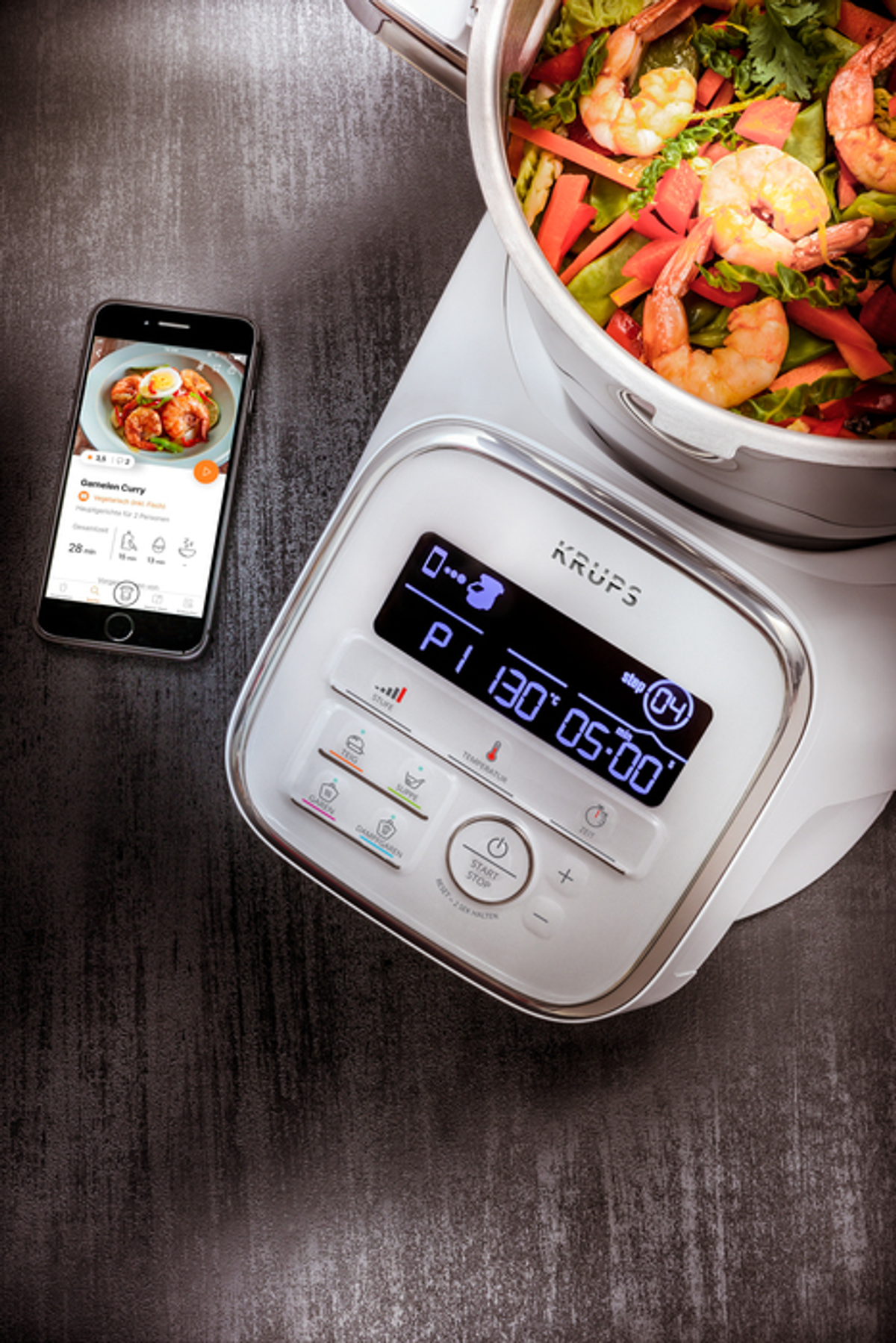 Ein Smartphone zeigt eine Essens-App. Eine Krups-Maschine hat einen Bildschirm mit Einstellungen, Essen daneben.
