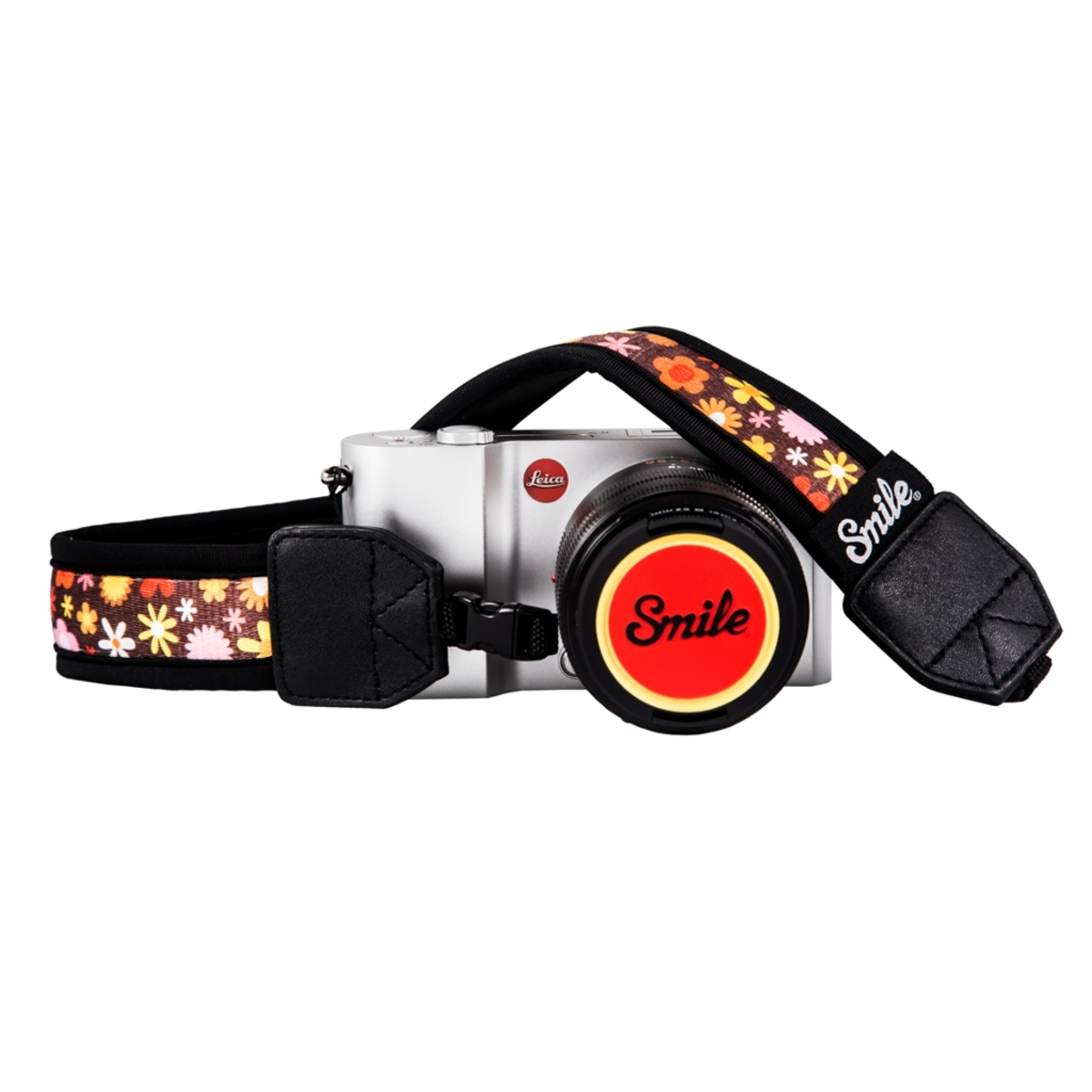 Una fotocamera Leica argentata con un cinturino floreale e un tappo dell'obiettivo rosso e bianco.