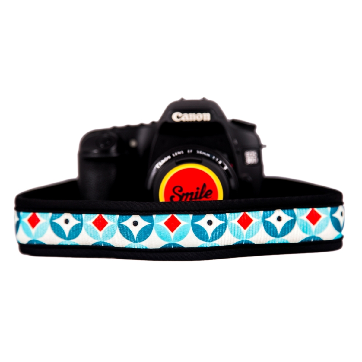 Fotocamera con cinturino rosso e blu con adesivo giallo 'Smile' sull'obiettivo.