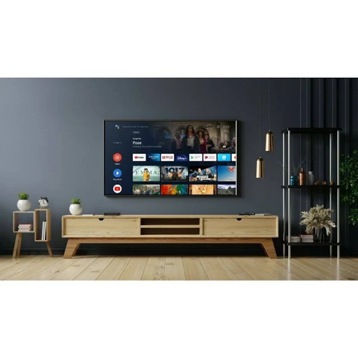Una grande TV su una parete, montata sopra un mobile in legno con piante e mensole.