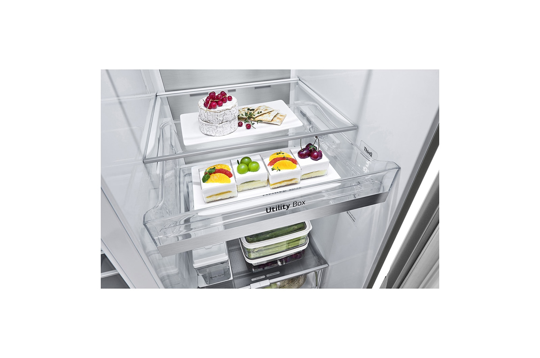 Otwarta lodówka z deserami na tacach. Widoczne ciasta i taca z jagodami.