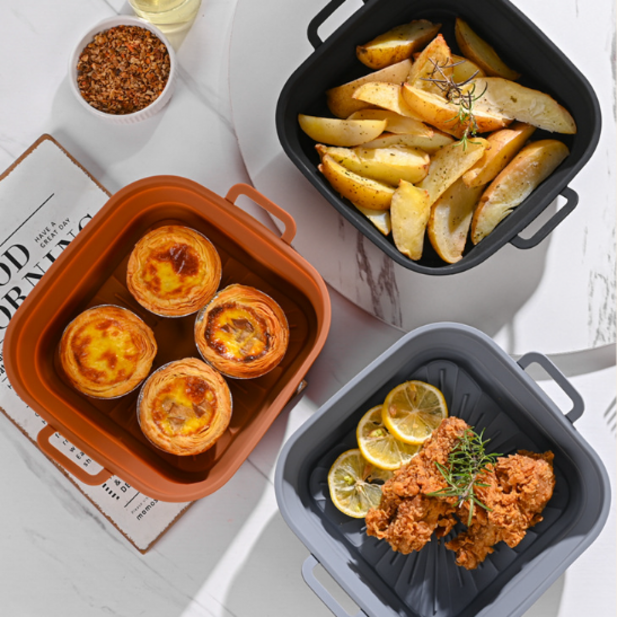 Drie siliconen bakken met eten: aardappelpartjes, eiertaartjes en gebakken kip met citroen.