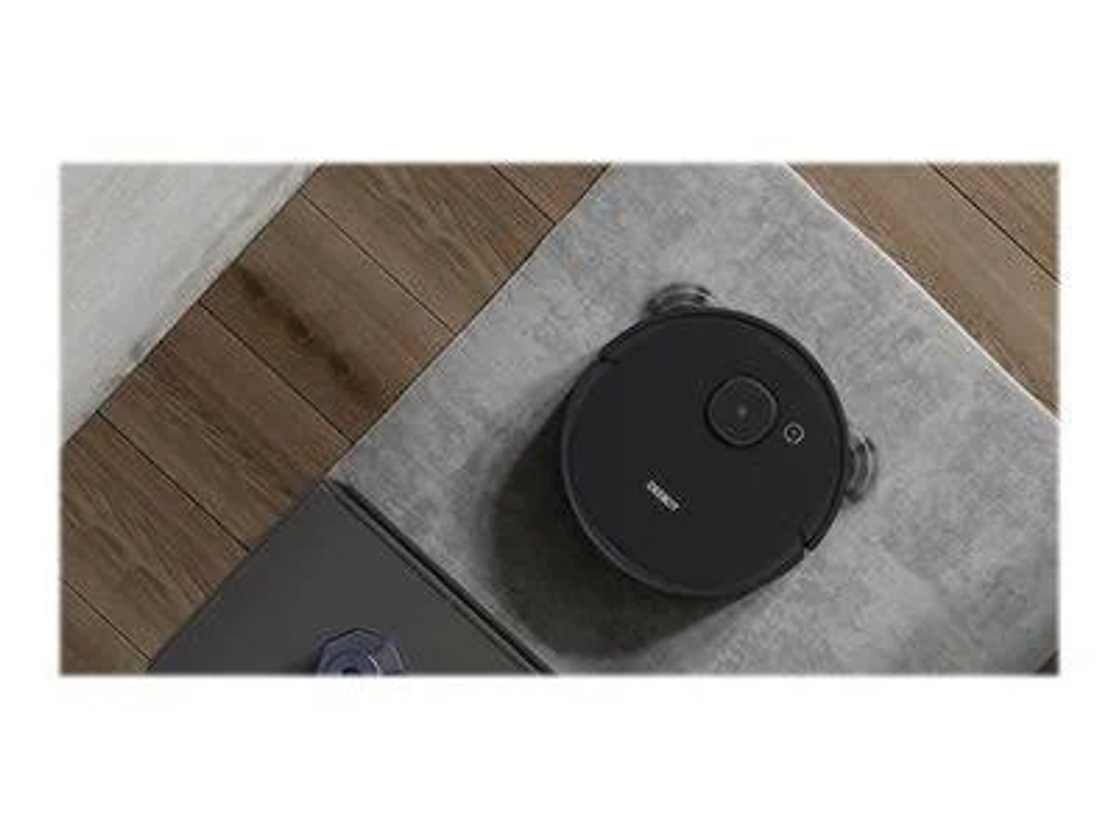 Schwarzer Roboter-Staubsauger auf grauer Oberfläche, mit einer Ecke einer dunklen Oberfläche.