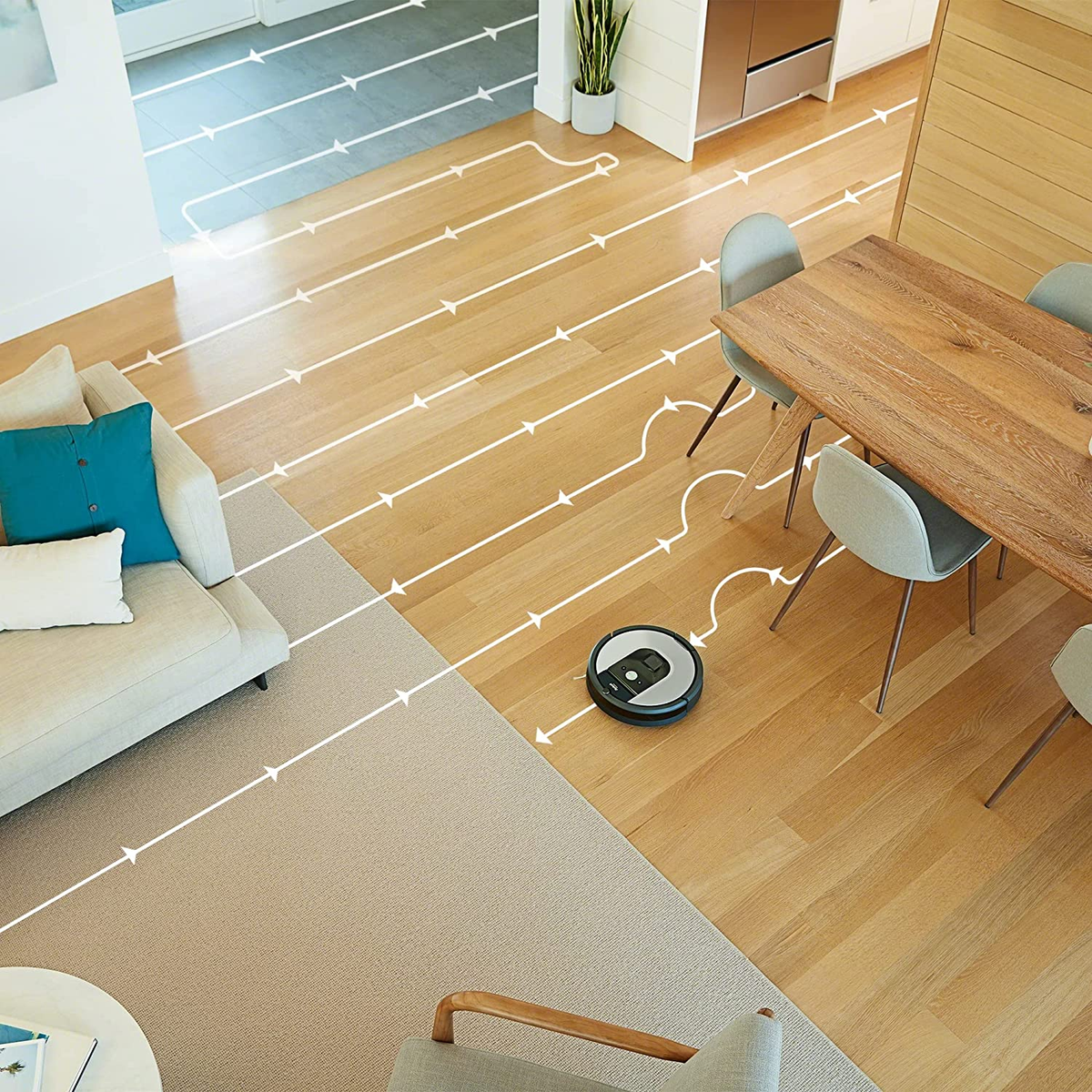 Robot sprzątający na drewnianej podłodze, zaznaczona ścieżka czyszczenia. Salon z sofą, stołem i krzesłami.
