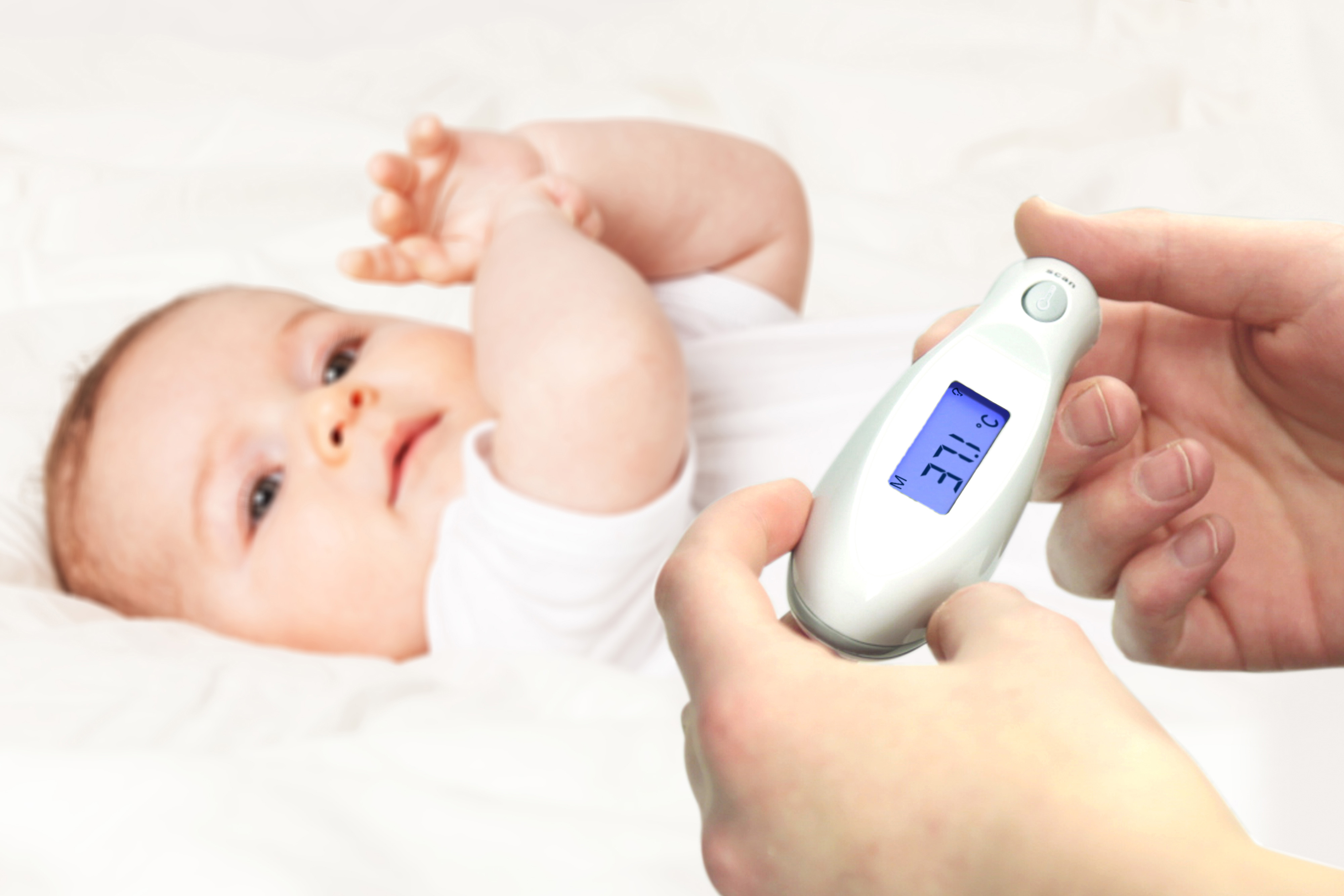 Ein Baby liegt mit einem Thermometer, das nahe gehalten wird.