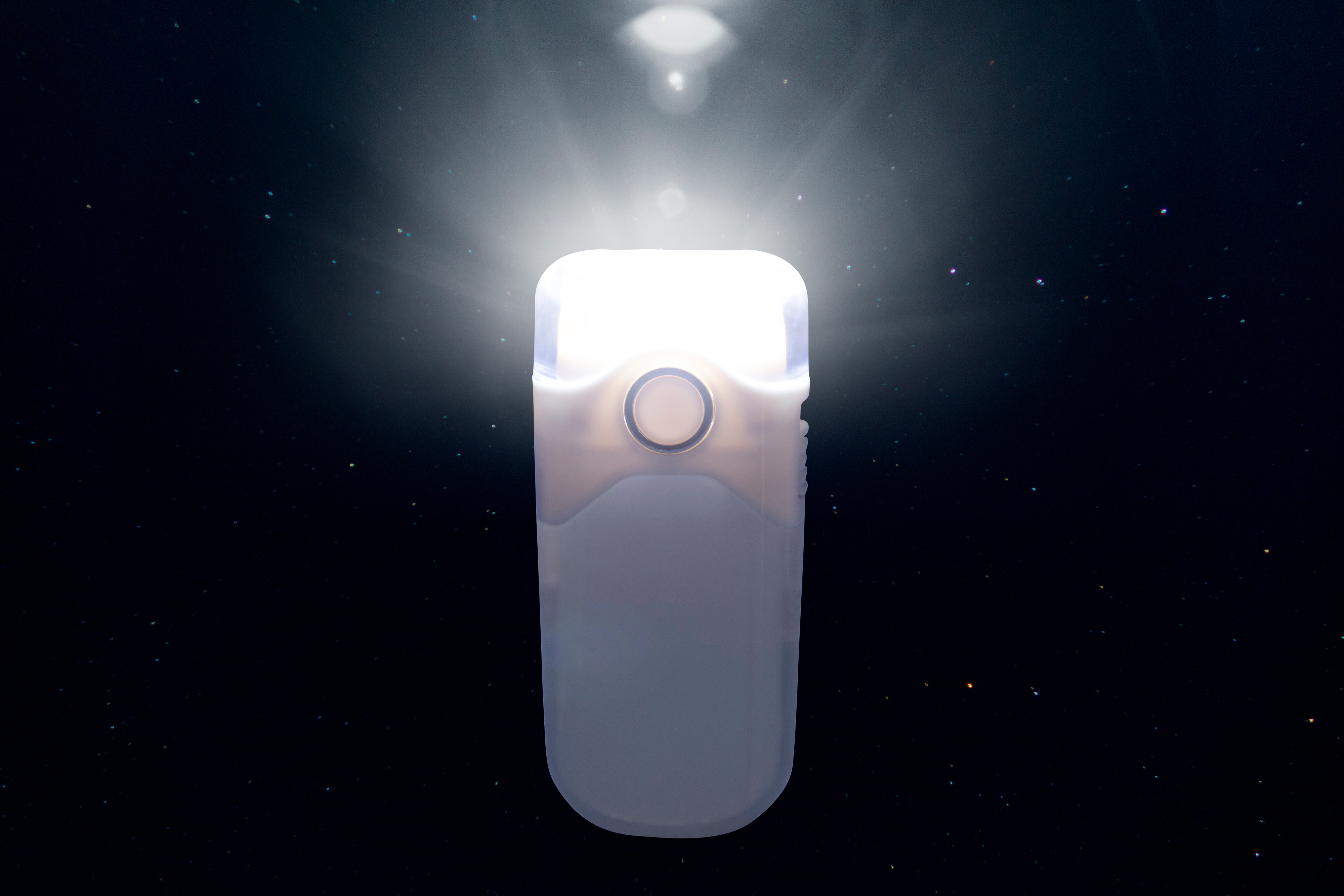 A white, rectangular nebulizer glows brightly against a dark background with stars.
