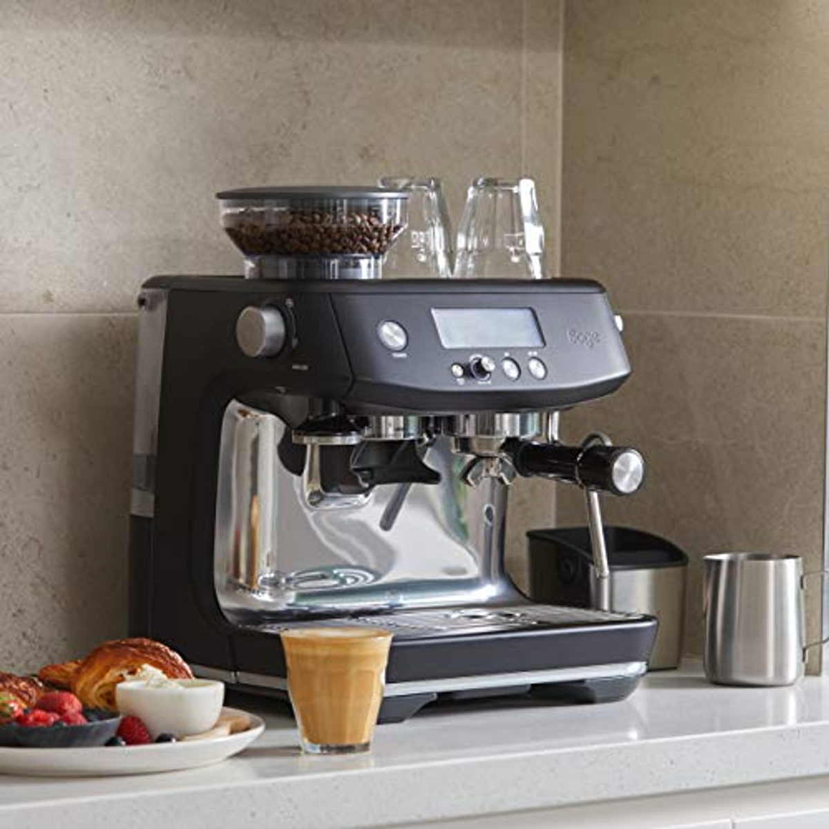 Espressomaschine mit Kaffee, Gebäck und Tassen. Edelstahl- und schwarzes Farbschema.