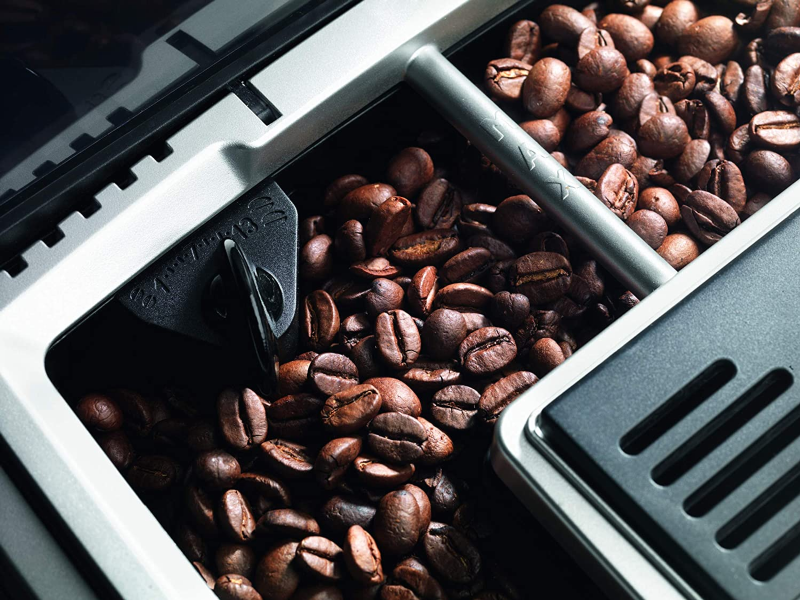 Granos de café dentro del contenedor de granos de una cafetera.