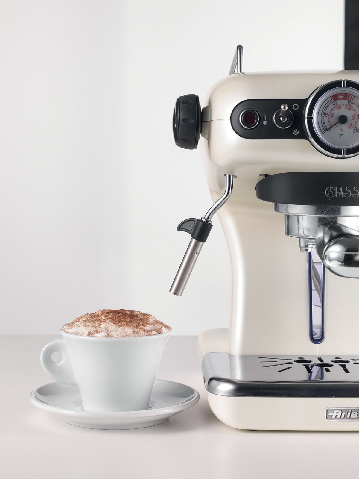 Máquina de espresso con una taza de capuchino y un fondo blanco, junto a la máquina.