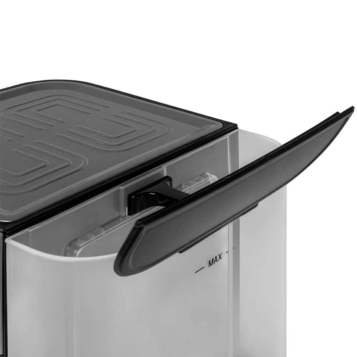 Zbliżenie zbiornika na wodę. Jest przezroczysty i ma czarną pokrywę. Pokazuje linię max.