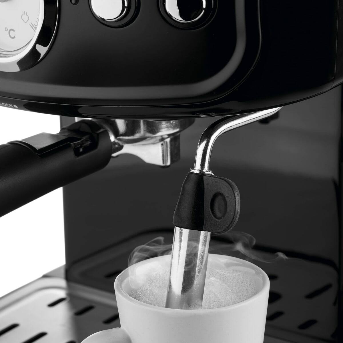 Primer plano de una máquina de espresso dispensando café en una taza blanca. El vapor se eleva del café.