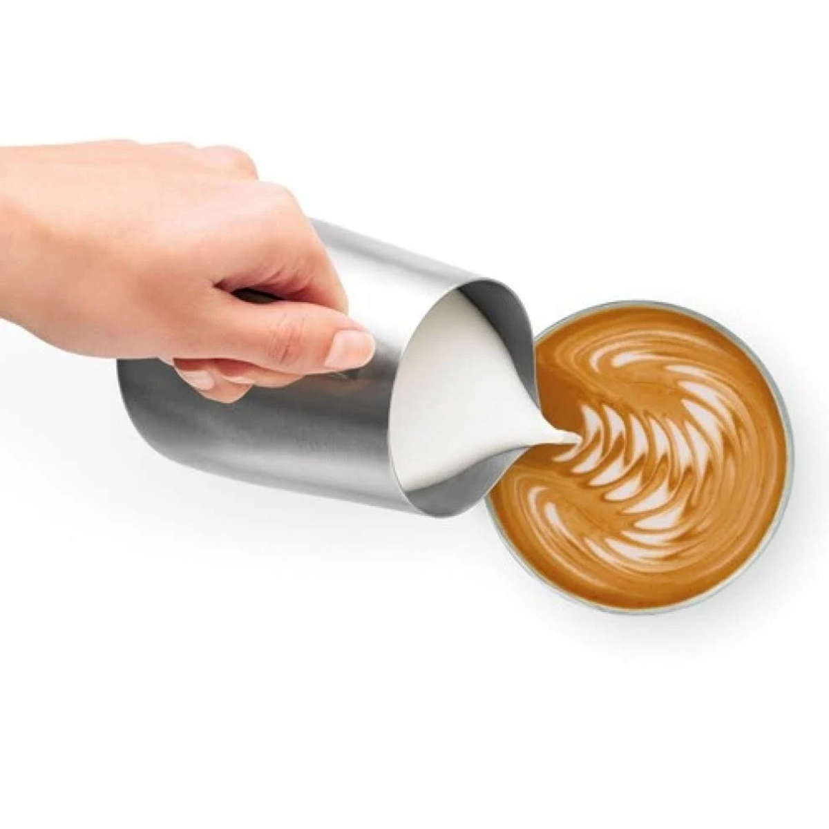 Une main verse du lait d'un pichet argenté dans une tasse de café avec du latte art.