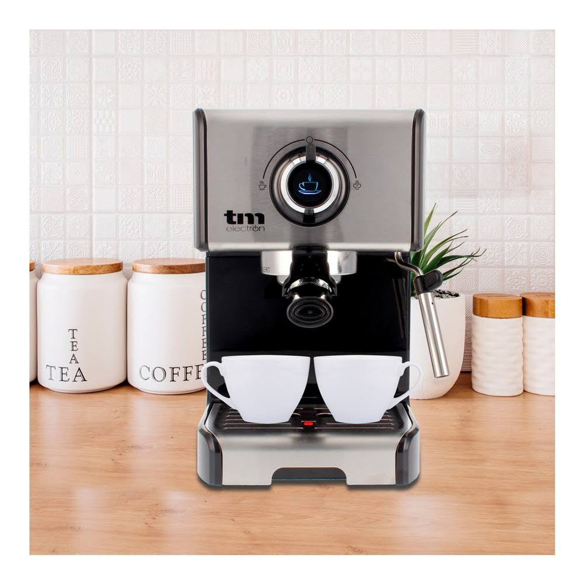 Máquina de espresso de acero inoxidable con tazas blancas, sobre una superficie de madera.