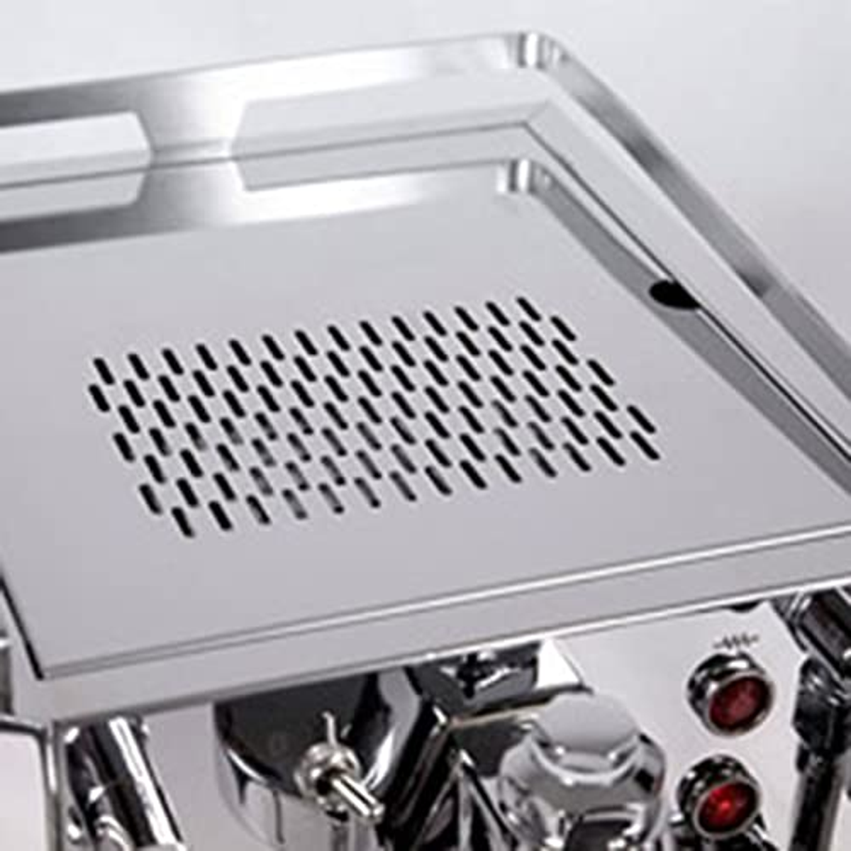 Zbliżenie tacy ociekowej ekspresu do kawy, pokazujące perforowaną metalową powierzchnię.