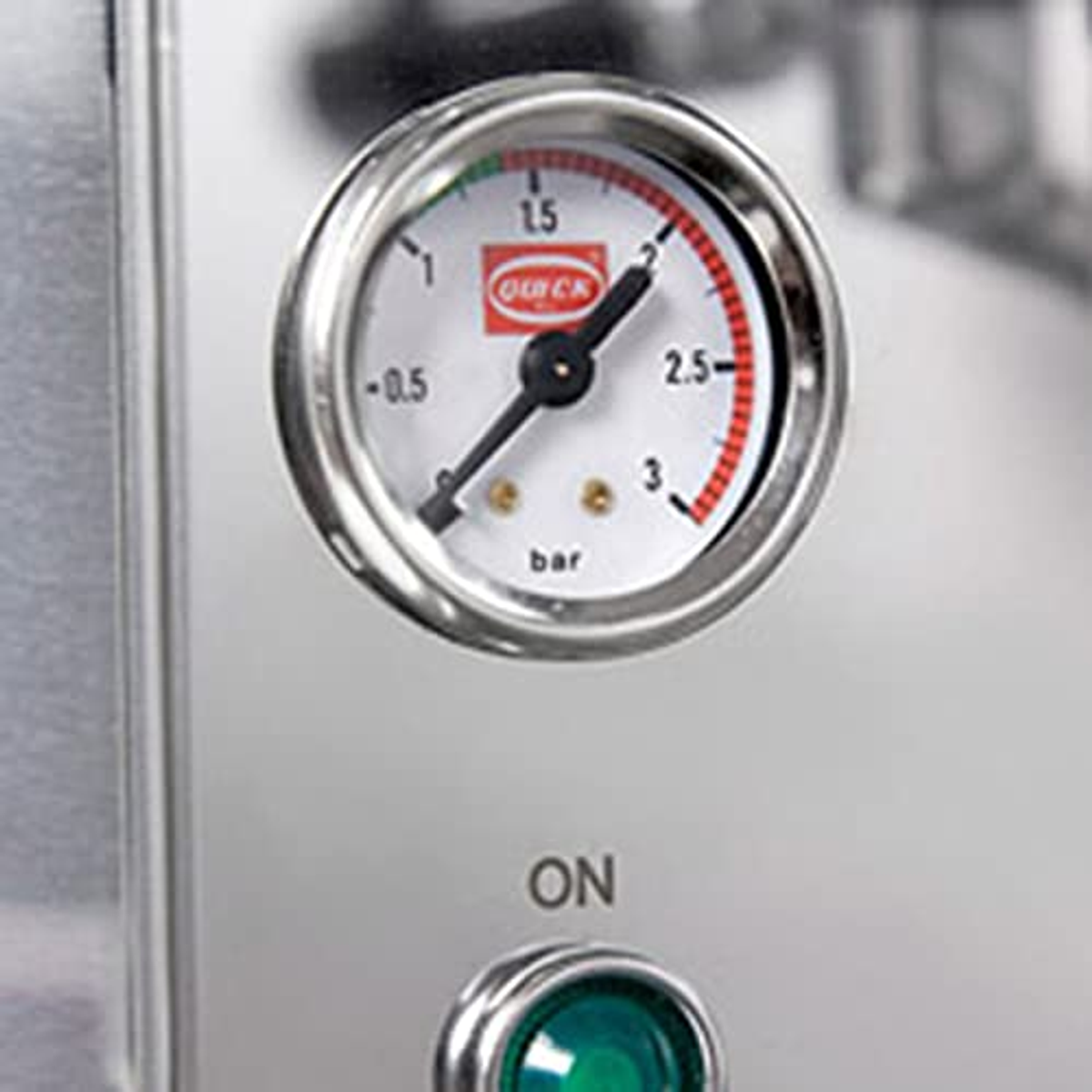 Zbliżenie manometru ekspresu do kawy. Wskaźnik pokazuje 2 bary. Widoczne słowo ON.
