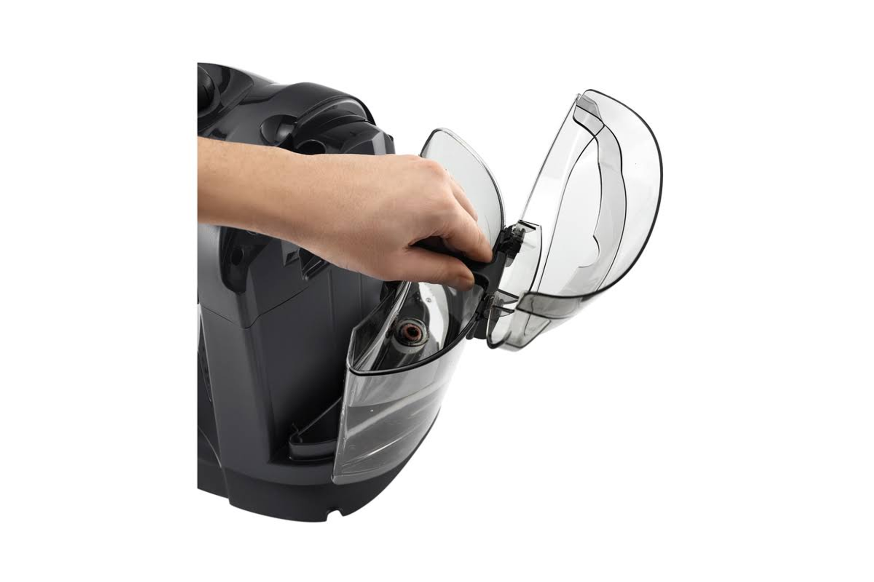 Ręka otwierająca pokrywę czarnego urządzenia, prawdopodobnie odkurzacza.