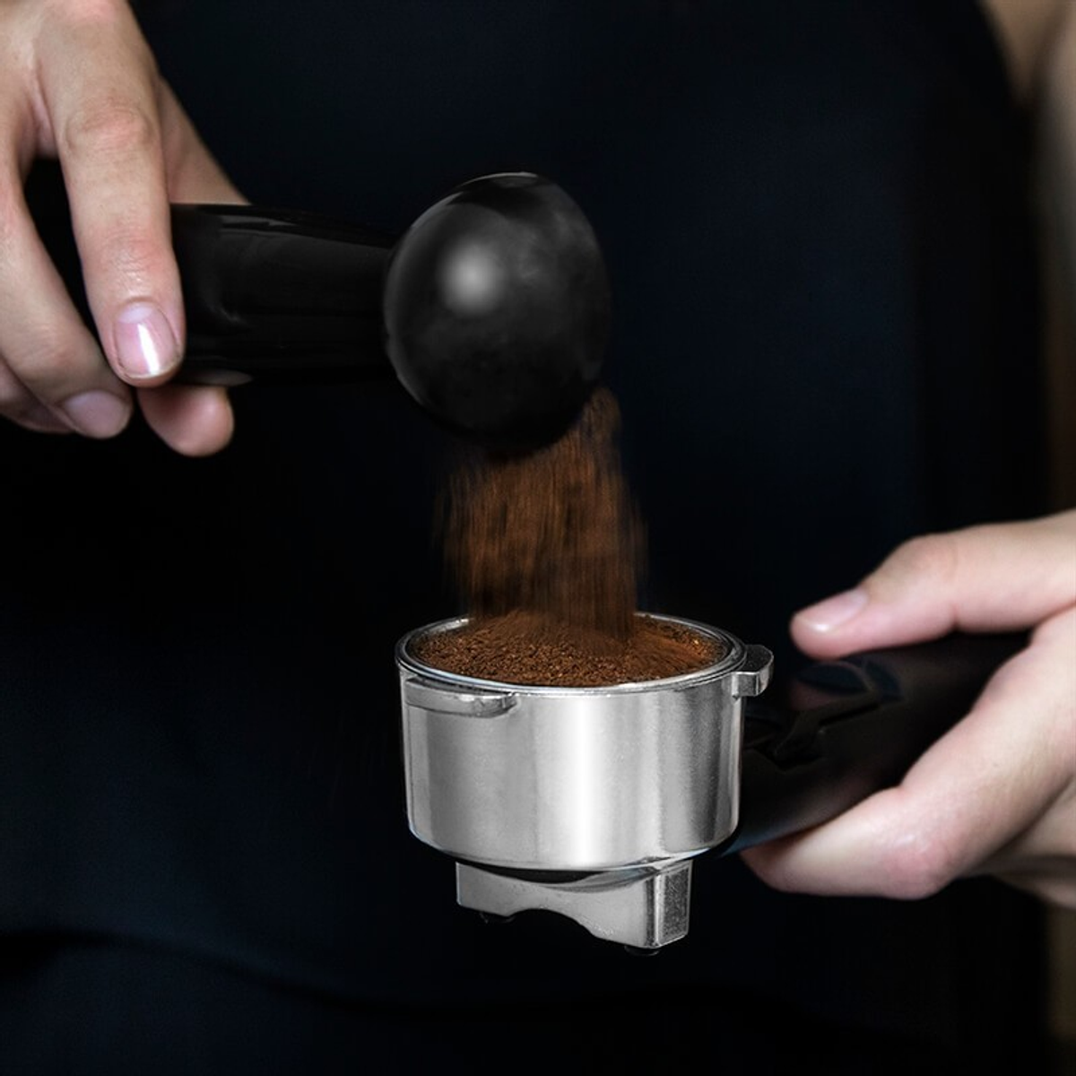 Hände gießen gemahlenen Kaffee in einen Siebträger.