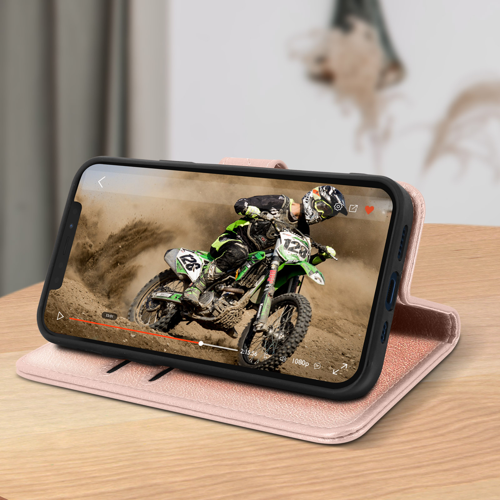 Telefono su una custodia rosa che mostra una scena di gara di moto, su una superficie di legno.