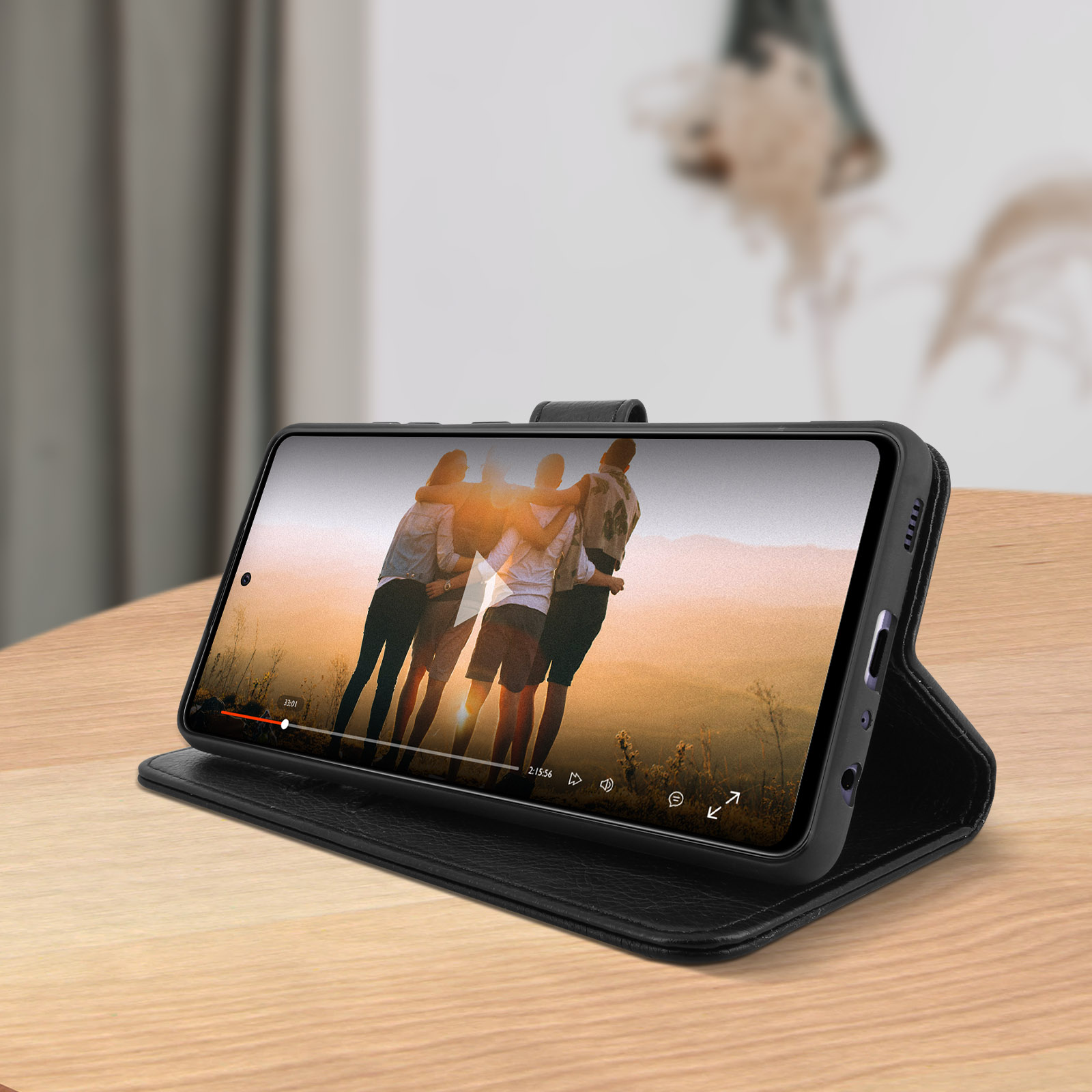 Smartphone dans un étui en cuir noir, affichant une vidéo sur une table en bois.