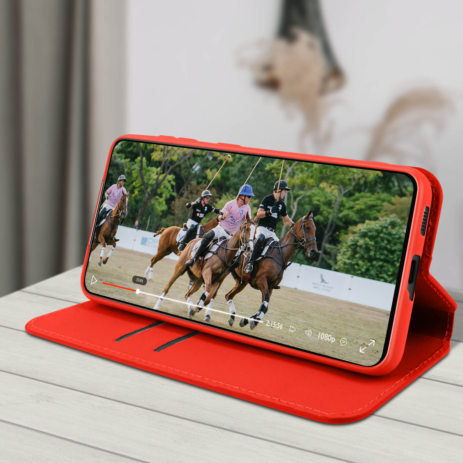 Smartphone che mostra una partita di polo in una custodia a portafoglio rossa.