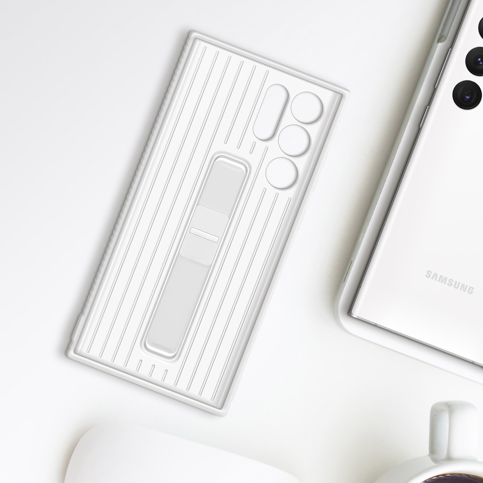 Funda blanca con soporte, teléfono y taza sobre una superficie blanca.