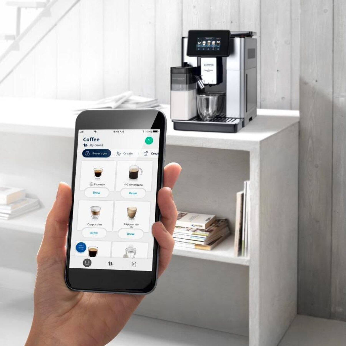 Una persona che tiene in mano un telefono con l'interfaccia dell'app di una macchina da caffè in cucina.