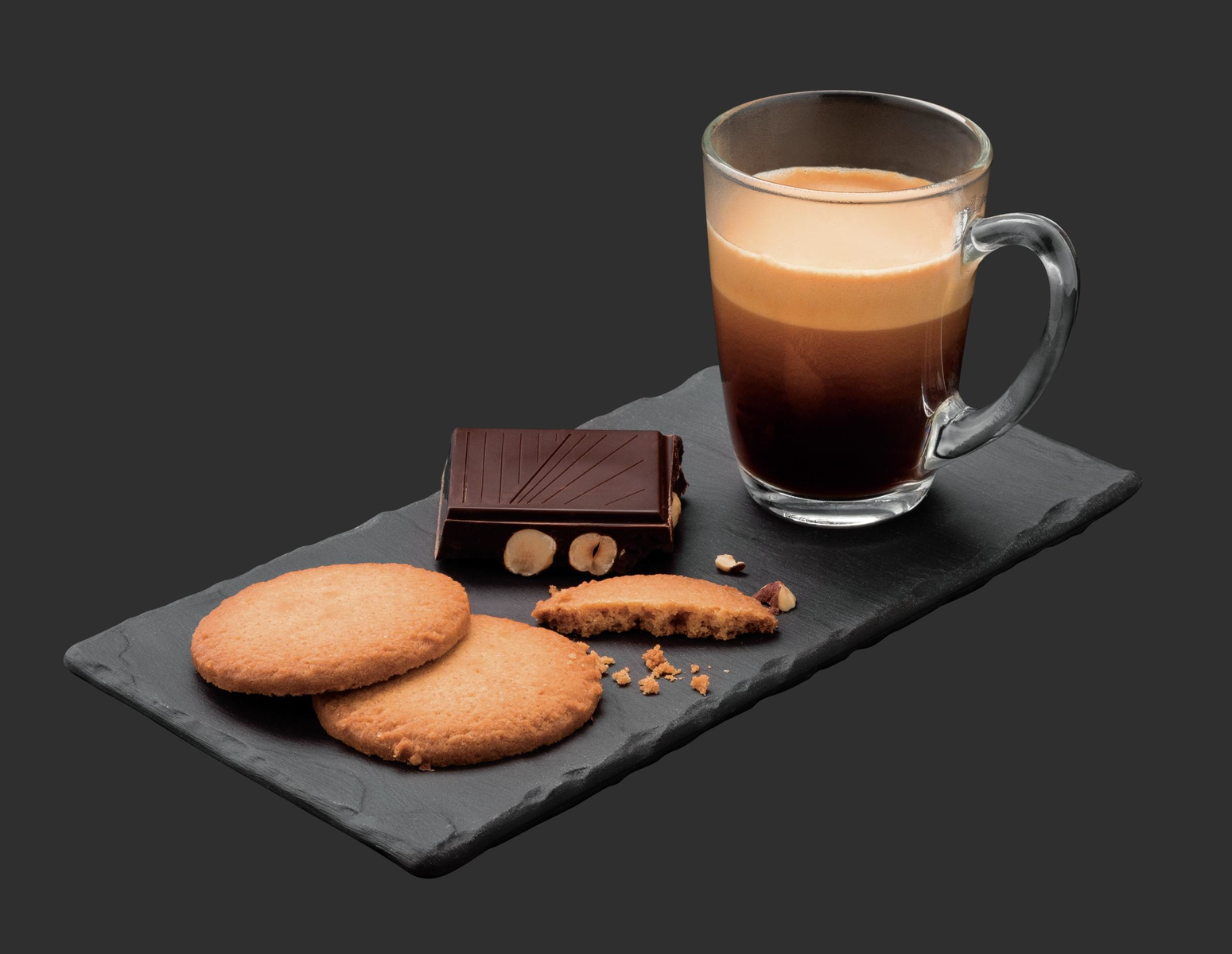 Kawa ze śmietanką, czekoladą i ciasteczkami na czarnym łupku, ciemne tło.
