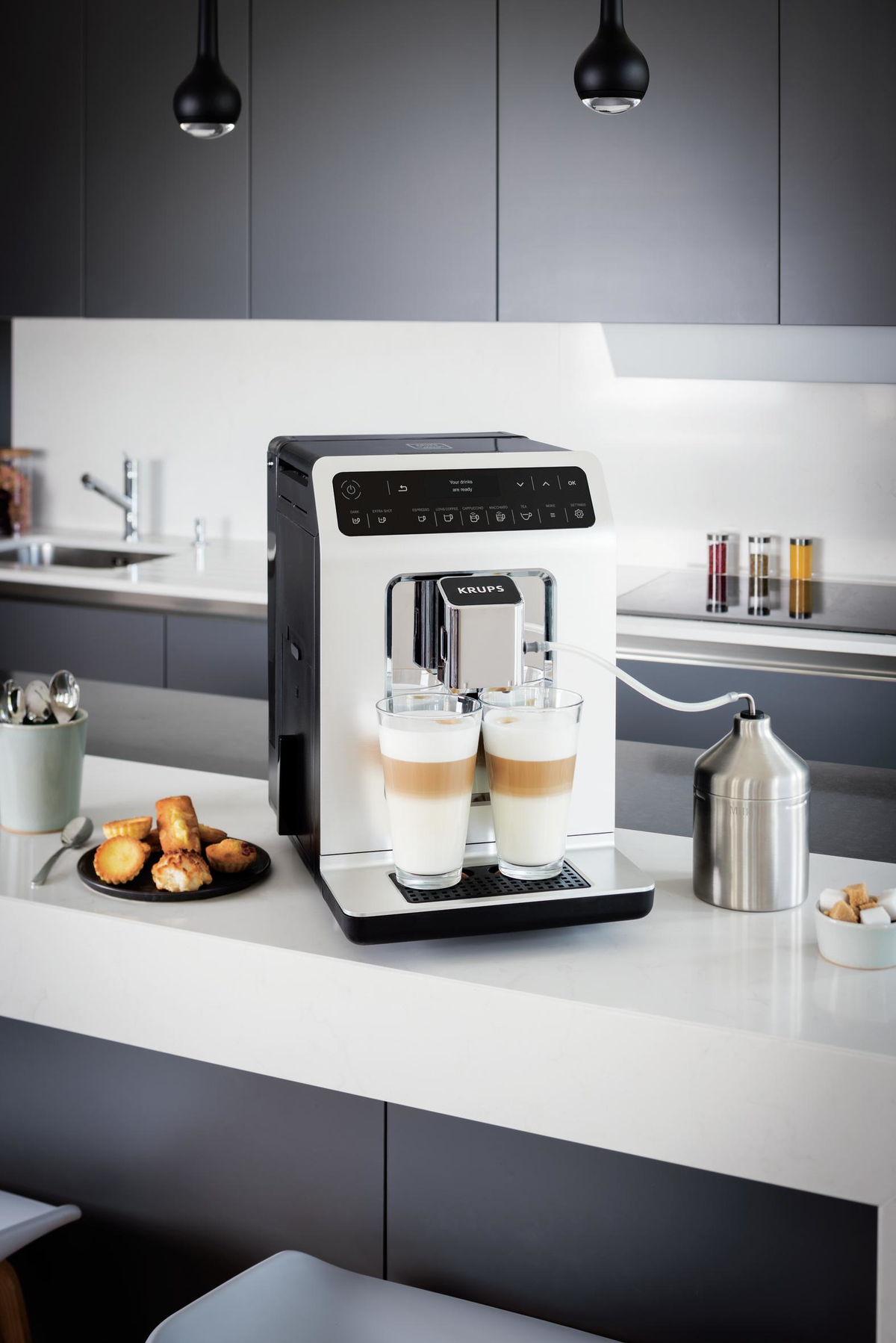 Biało-czarny ekspres do kawy Krups z dwoma szklankami latte na blacie.