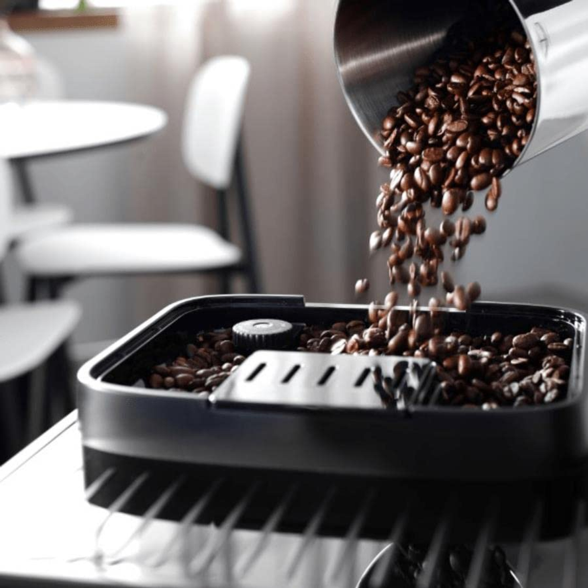 Ziarna kawy wlewane z metalowego pojemnika do zbiornika na ziarna ekspresu do kawy.
