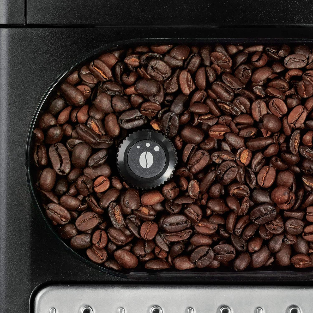 I chicchi di caffè riempiono il contenitore di una macchina da caffè, con un quadrante nero al centro.