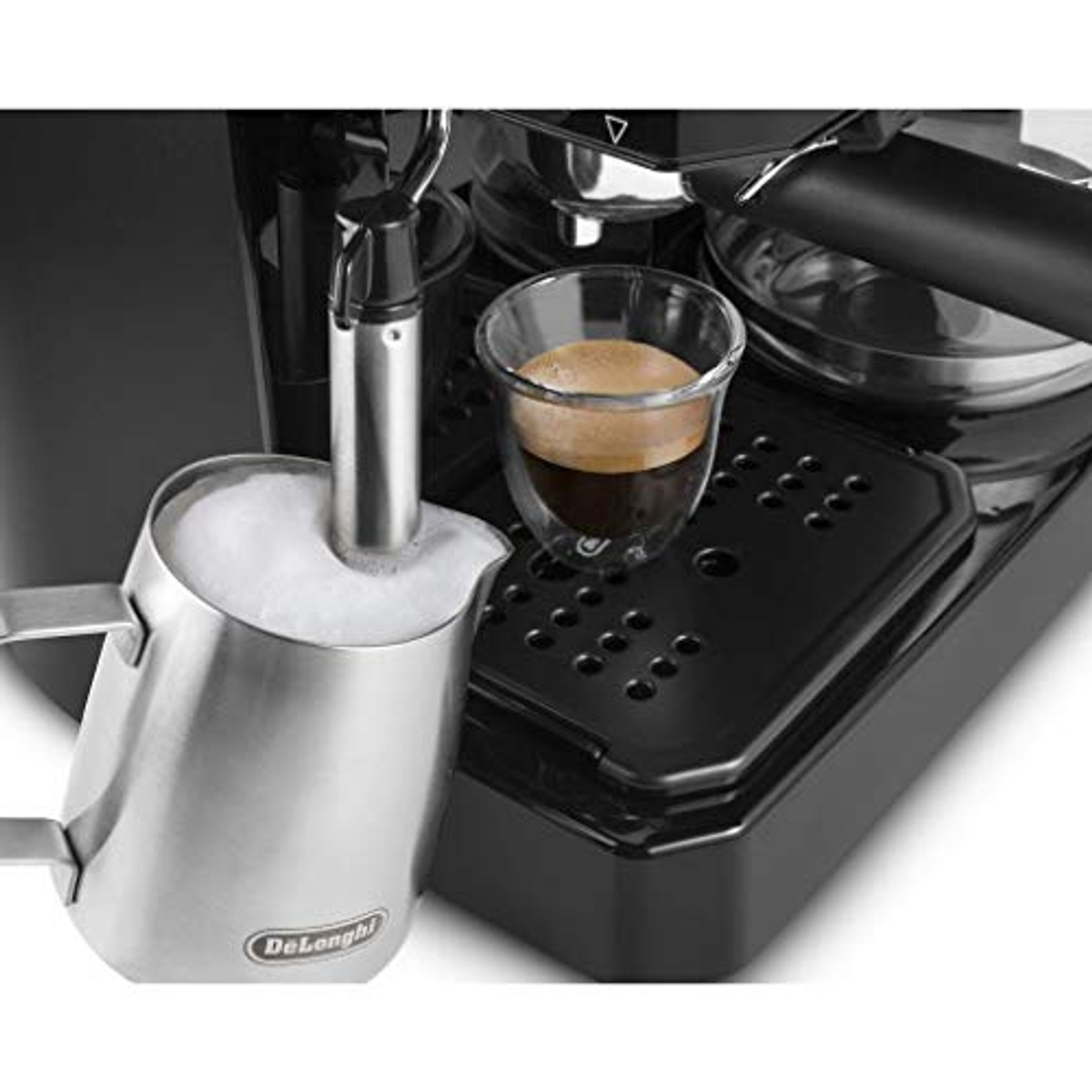 Espressomaschine mit einem Milchaufschäumkännchen und einem Glas Espresso auf schwarzer Oberfläche.