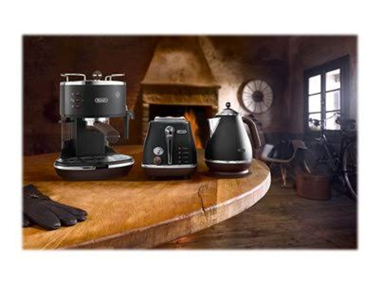 Zestaw czarnych urządzeń kuchennych na drewnianym stole. Obejmuje ekspres do kawy, toster i czajnik.